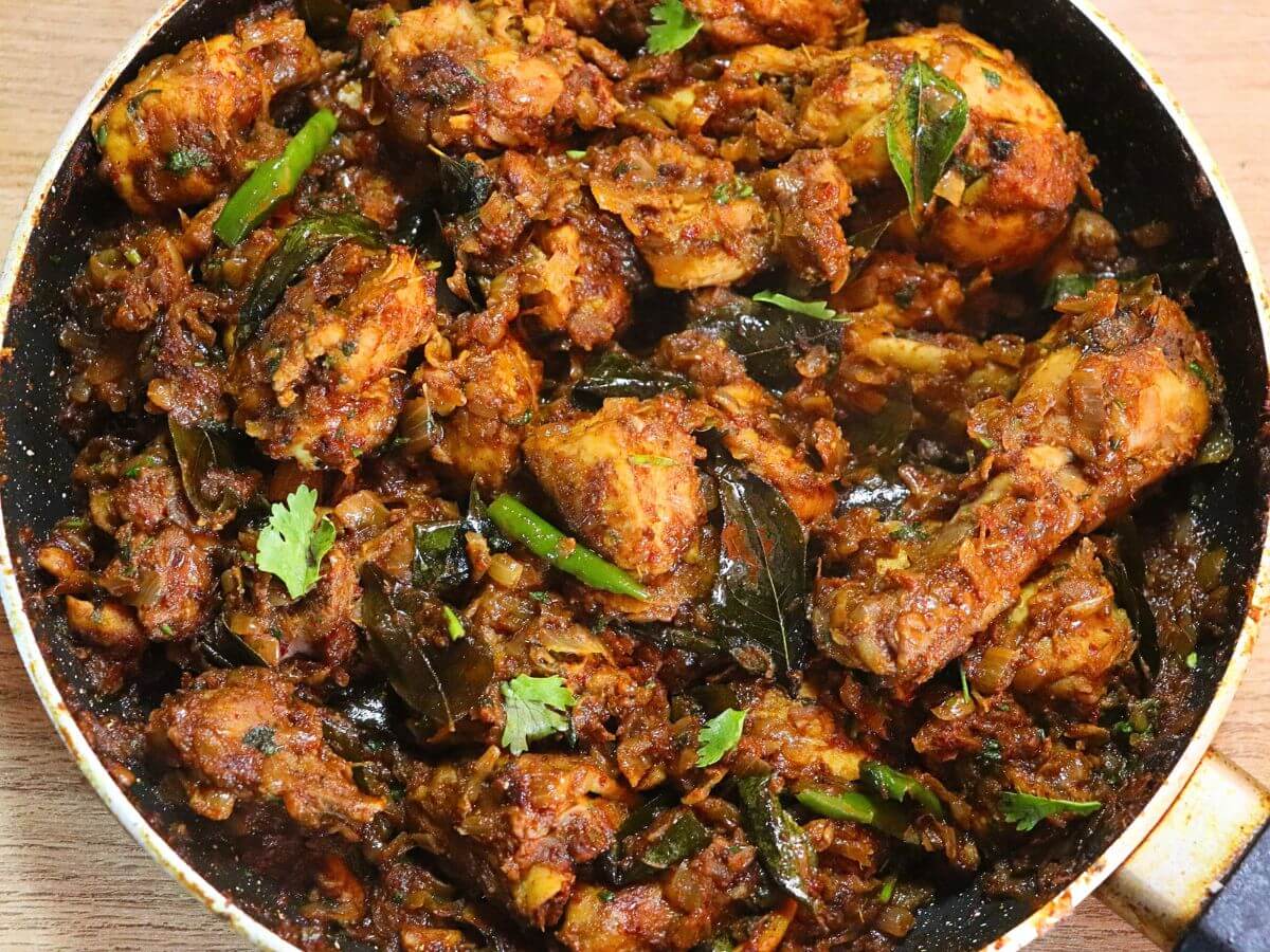 Andhra Kodi Vepudu in a pan, garnished with curry leaves.