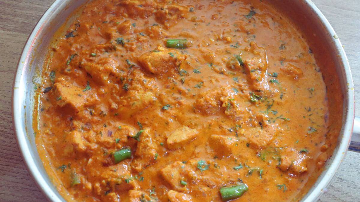garlic chicken curry in a pan. Garnished with coriander leaves.