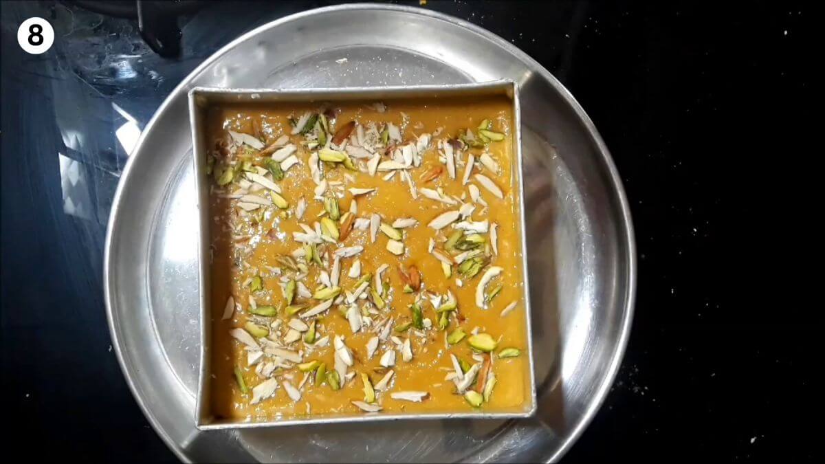 transfering the besan and sugar syrup mixture to the burfi mould.