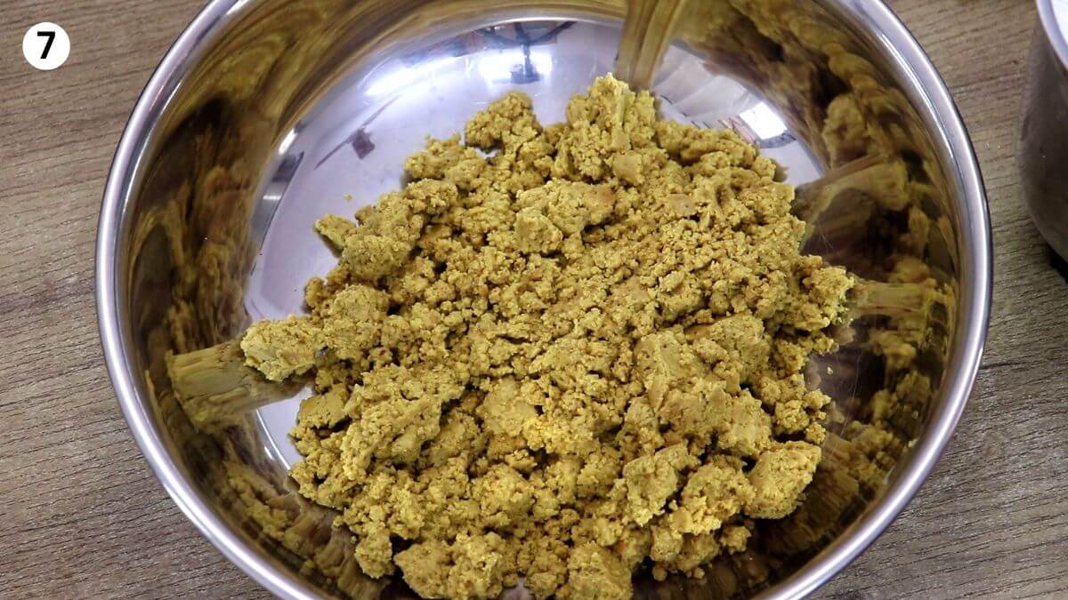 transferring roasted besan to make ladoo to a large mixing bowl.