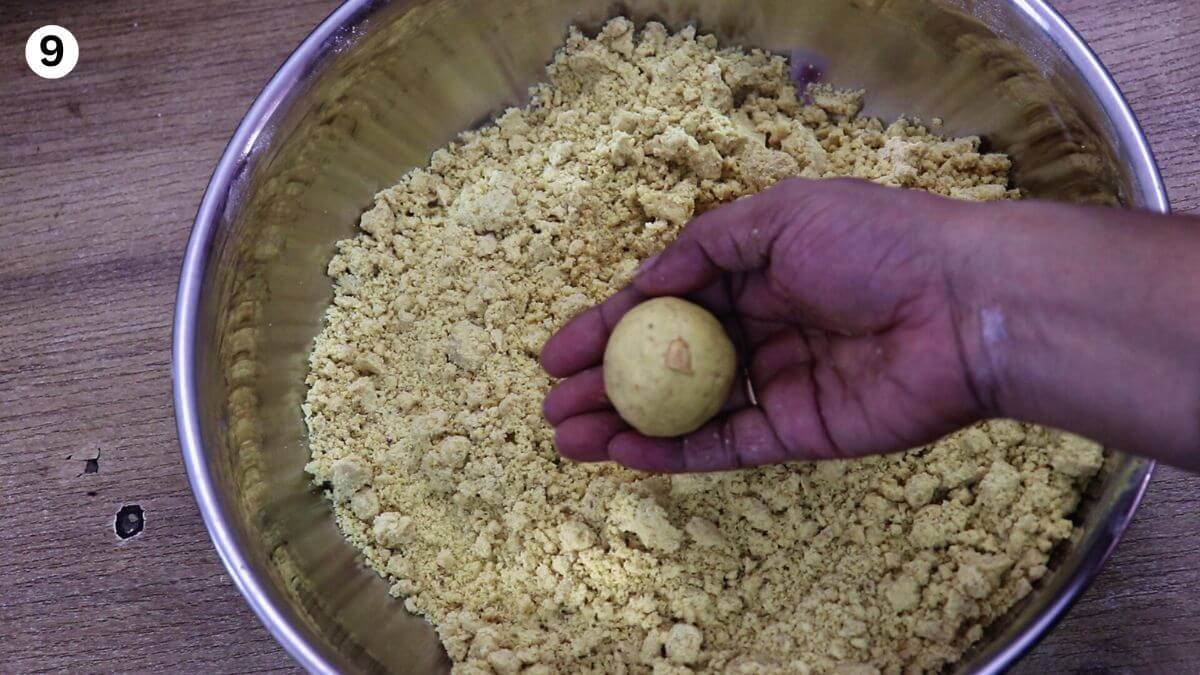 shaping a besan ladoo from the mixture, with one ladoo held in hand.