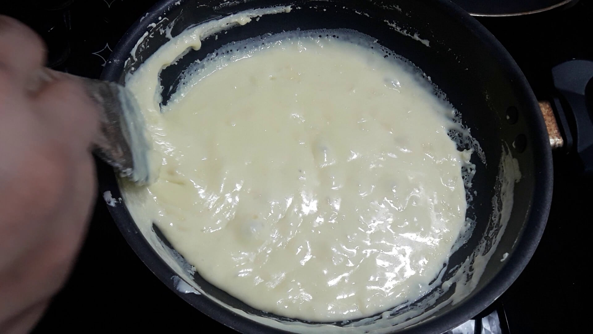 Heating the milk powder mixture and scraping the sides to make instant mawa.