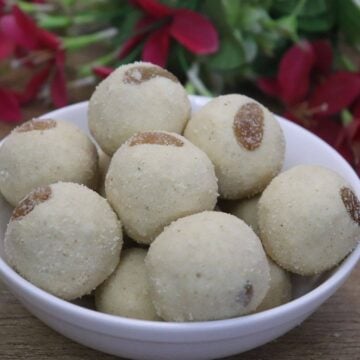 Maharashtrian Rava Ladoo placed on a white bowl on a brown counter top.