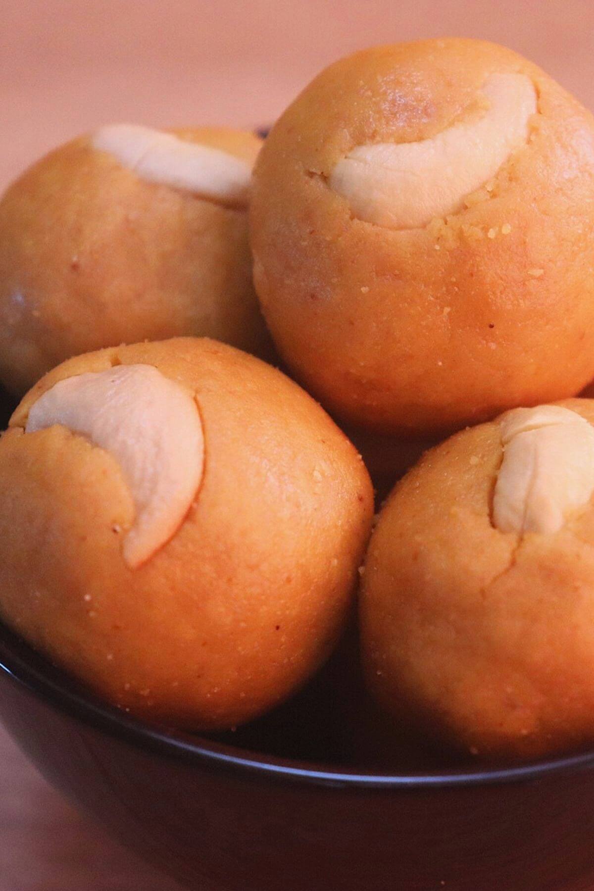 moong dal ladoo stacked on a black color bowl.