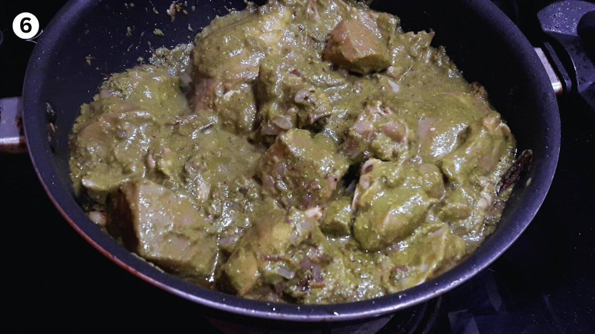 cooking the marinated chicken in green paste to make hyderabadi chicken curry.