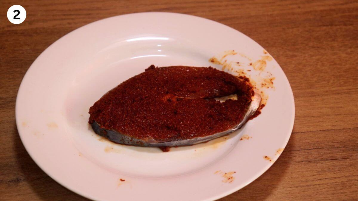 applying the spicy masala paste to the fish.