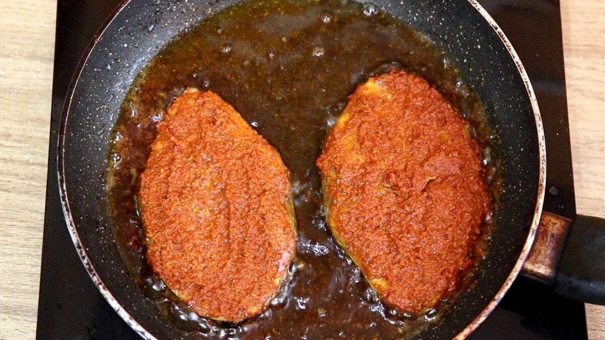 Pan-frying the marinated fish in oil to until golden and crispy.