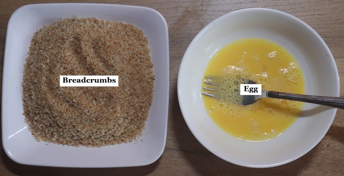 A bowl of breadcrumbs and a bowl of whisked eggs placed on a table.