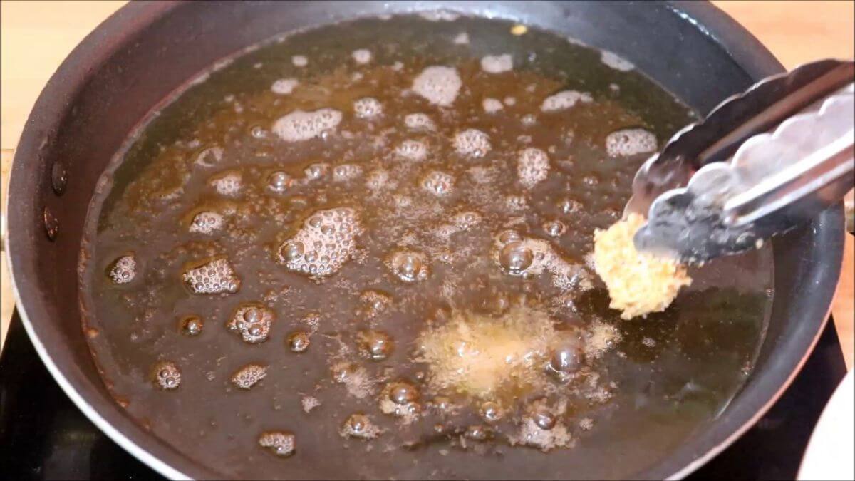 adding raw breaded chicken nuggets in hot oil to fry.