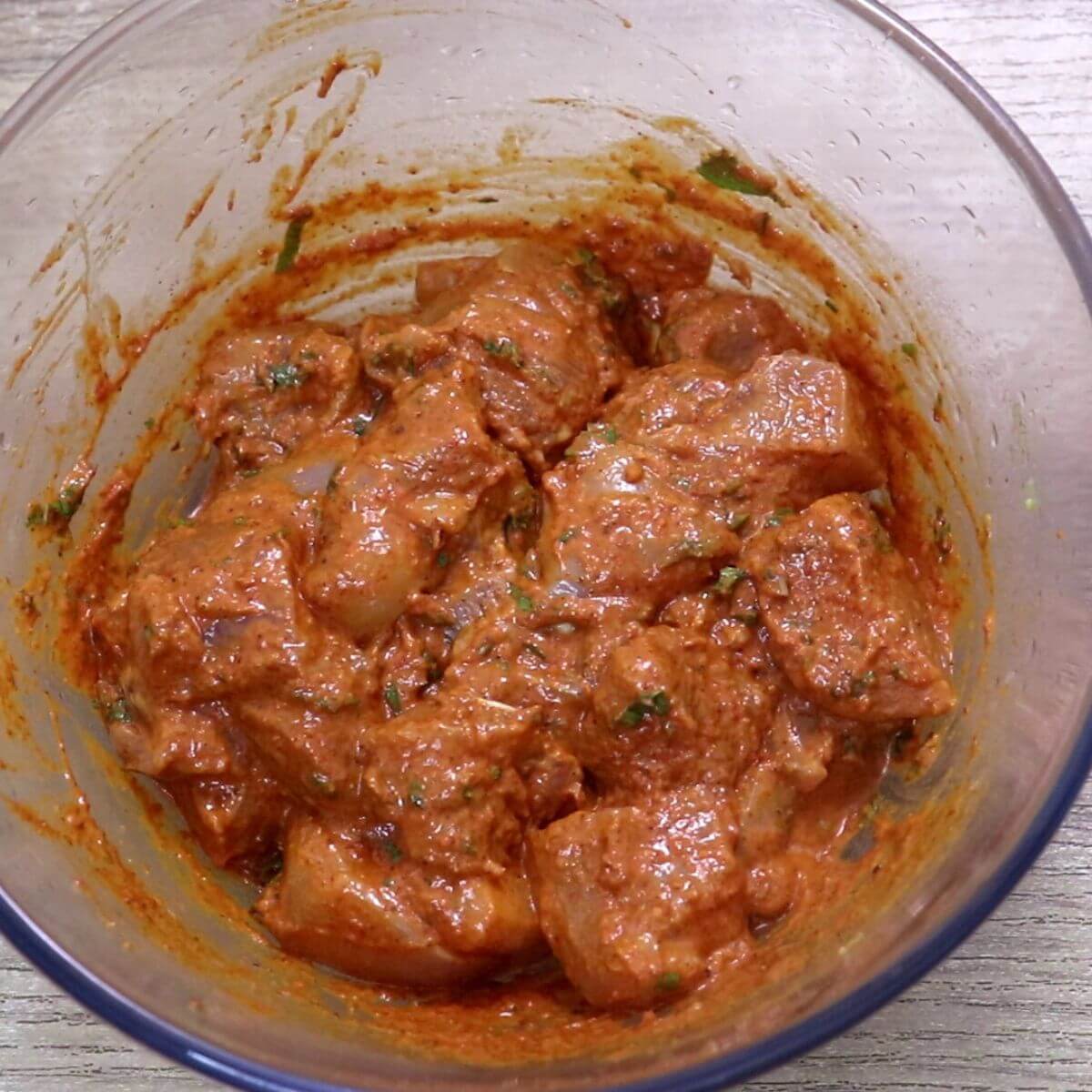 Harissa marinated chicken in a bowl, ready for grilling skewers.