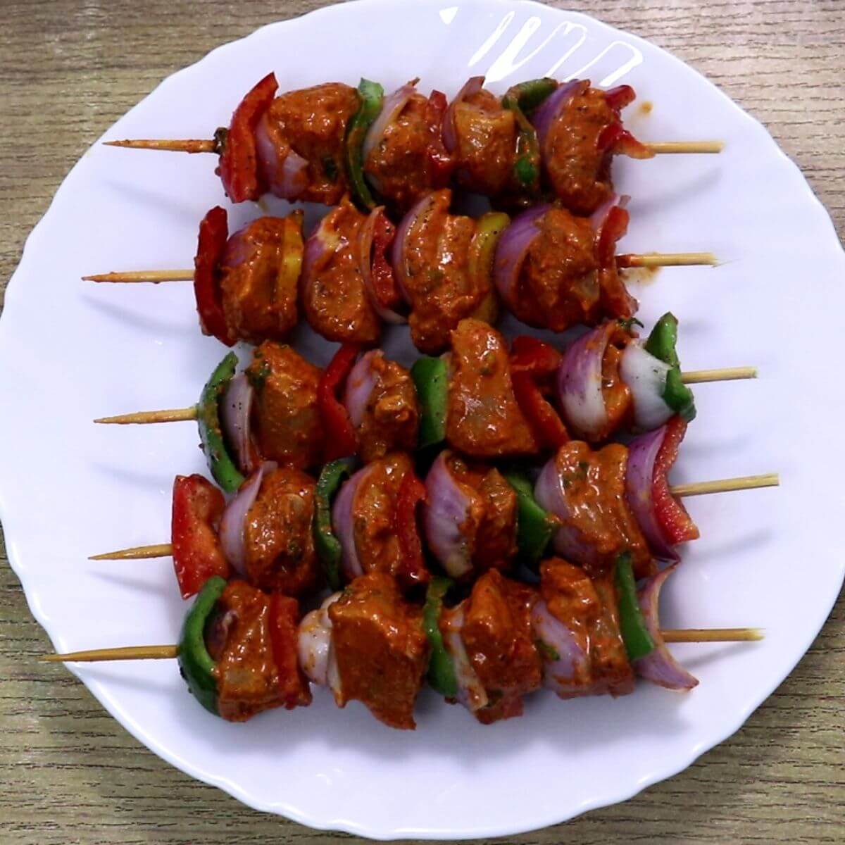 Skewered harissa chicken skewers served on a plate.
