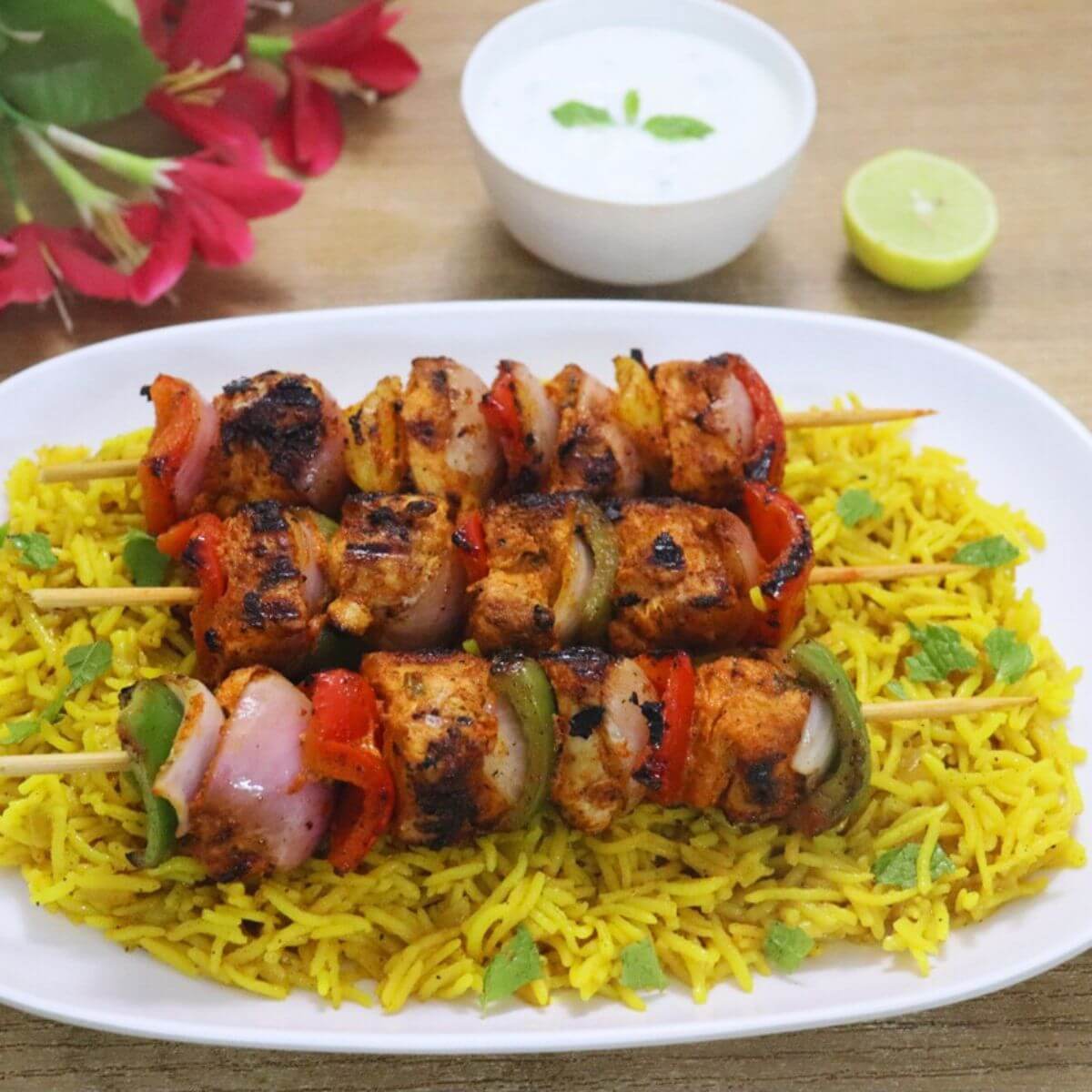 Harissa chicken skewers arranged on a plate of fluffy yellow rice.