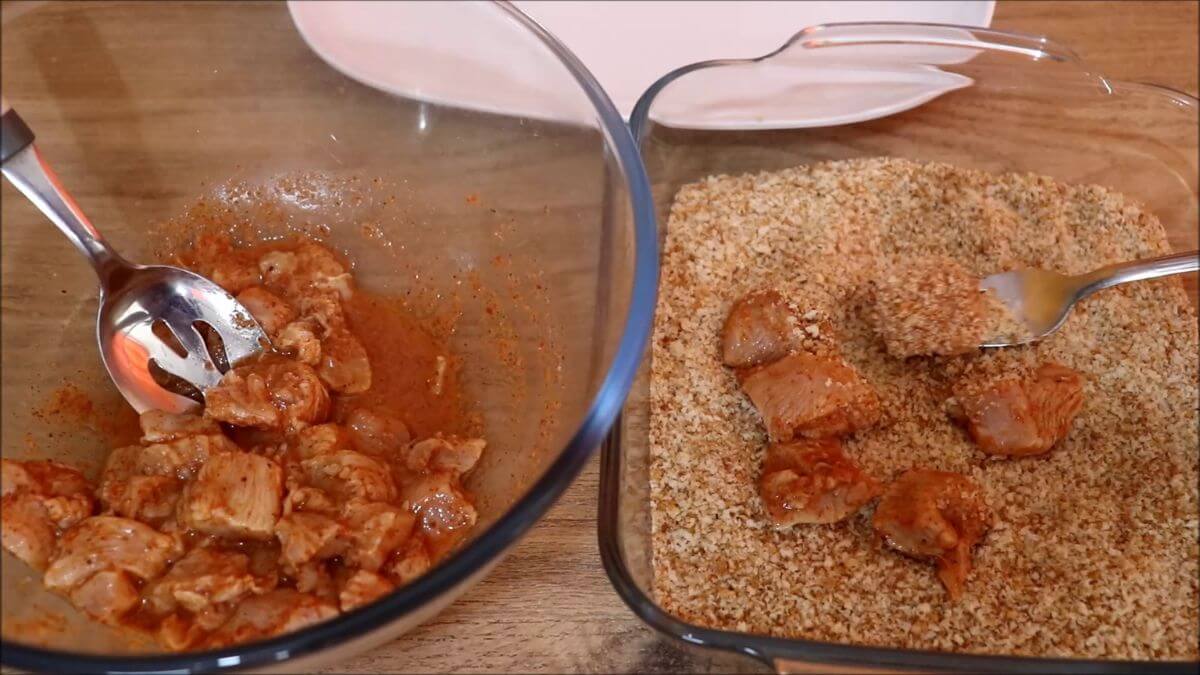 coating the chicken pieces with breadcrumbs to make homemade popcorn chicken.