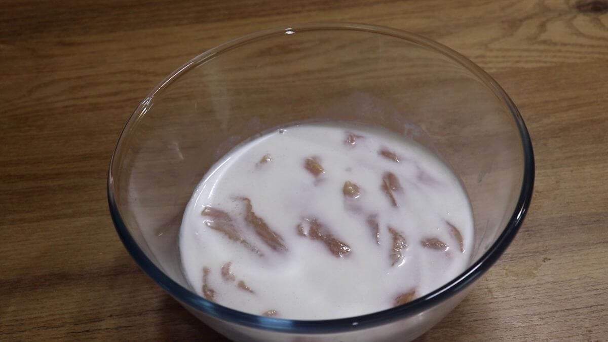 soaking chicken pieces in salted buttermilk in a bowl.