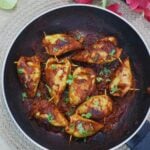 stuffed squids garnished with coriander leaves in a pan.