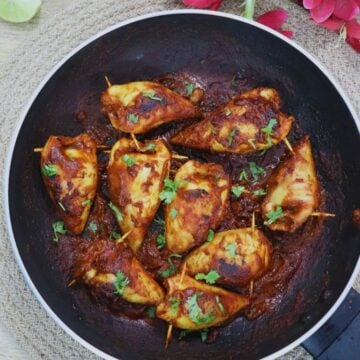 stuffed squids garnished with coriander leaves in a pan.