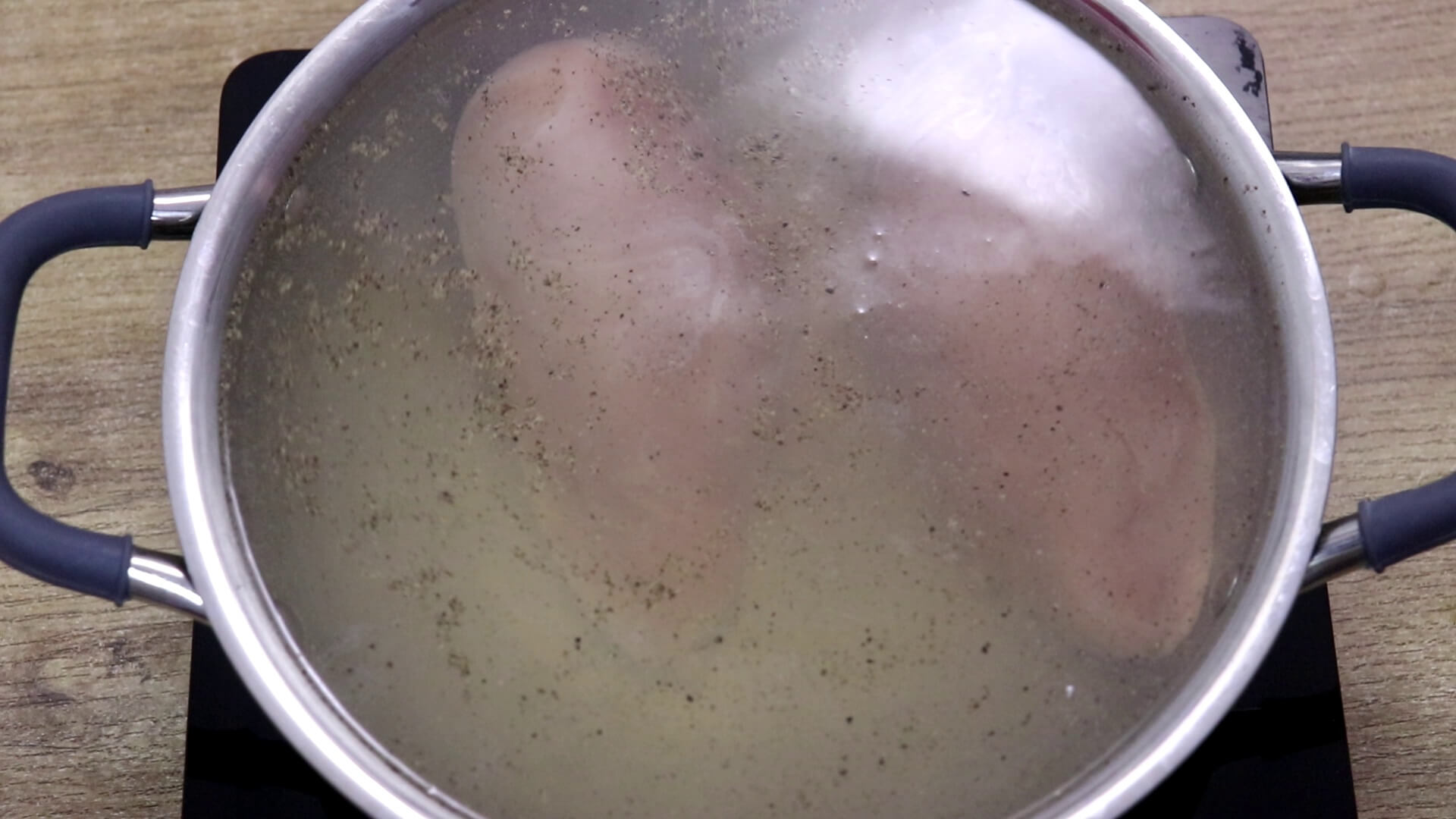 Boiling chicken in water for shredded chicken recipe.