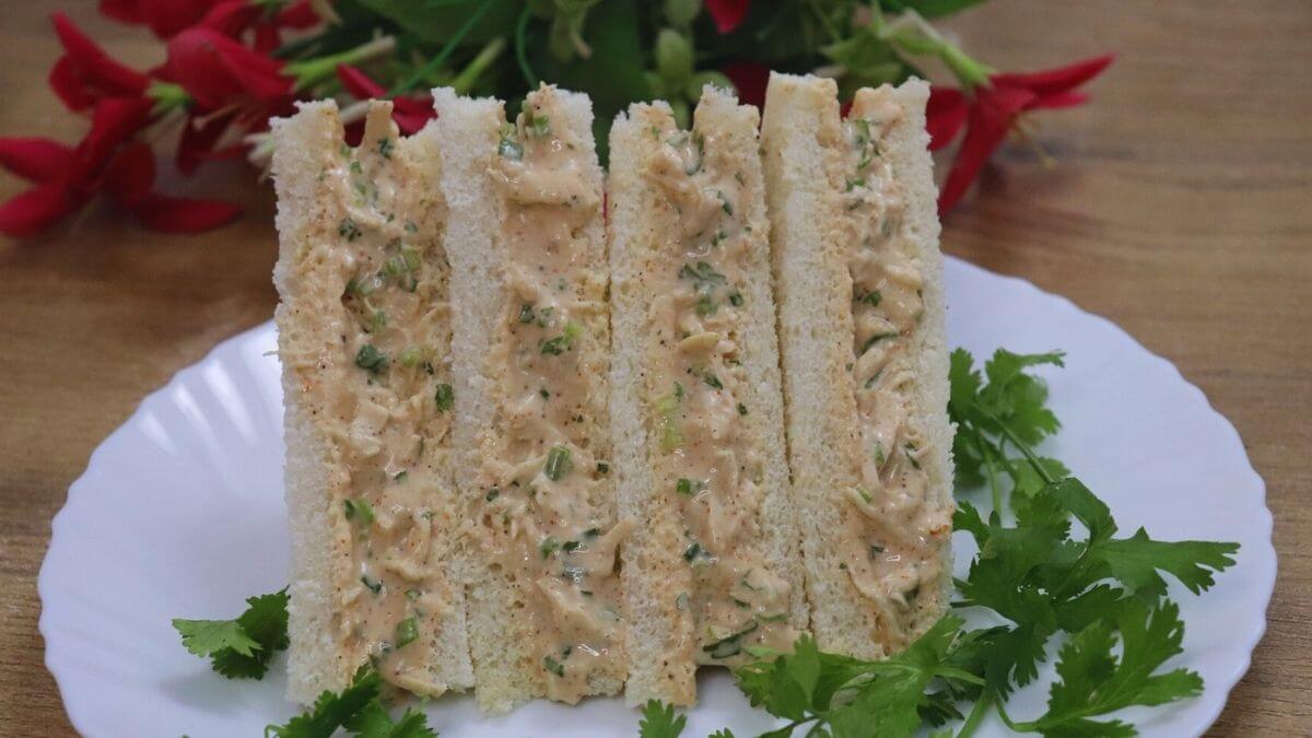 Chicken mayo sandwich made with shredded chicken, creamy mayonnaise, and fresh vegetables, placed on a white color plate.