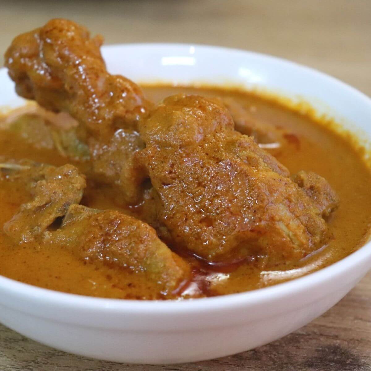 chicken xacuti served in a white bowl.