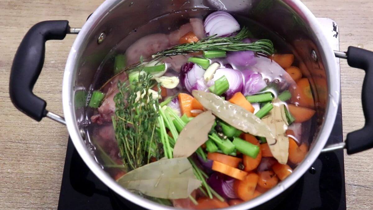 Chicken bones, Onions, carrots, celery, garlic, and herbs added to a stock pot.