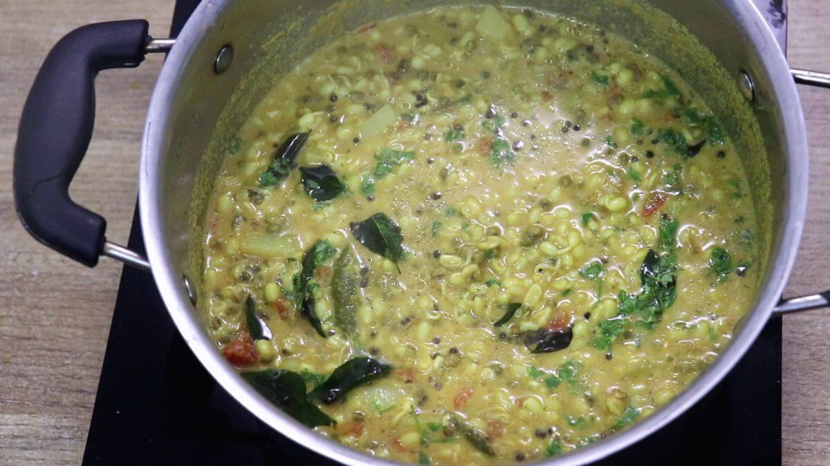 adding tempering to mooga gathi and garnishing the moong sprouts curry with coriander leaves.