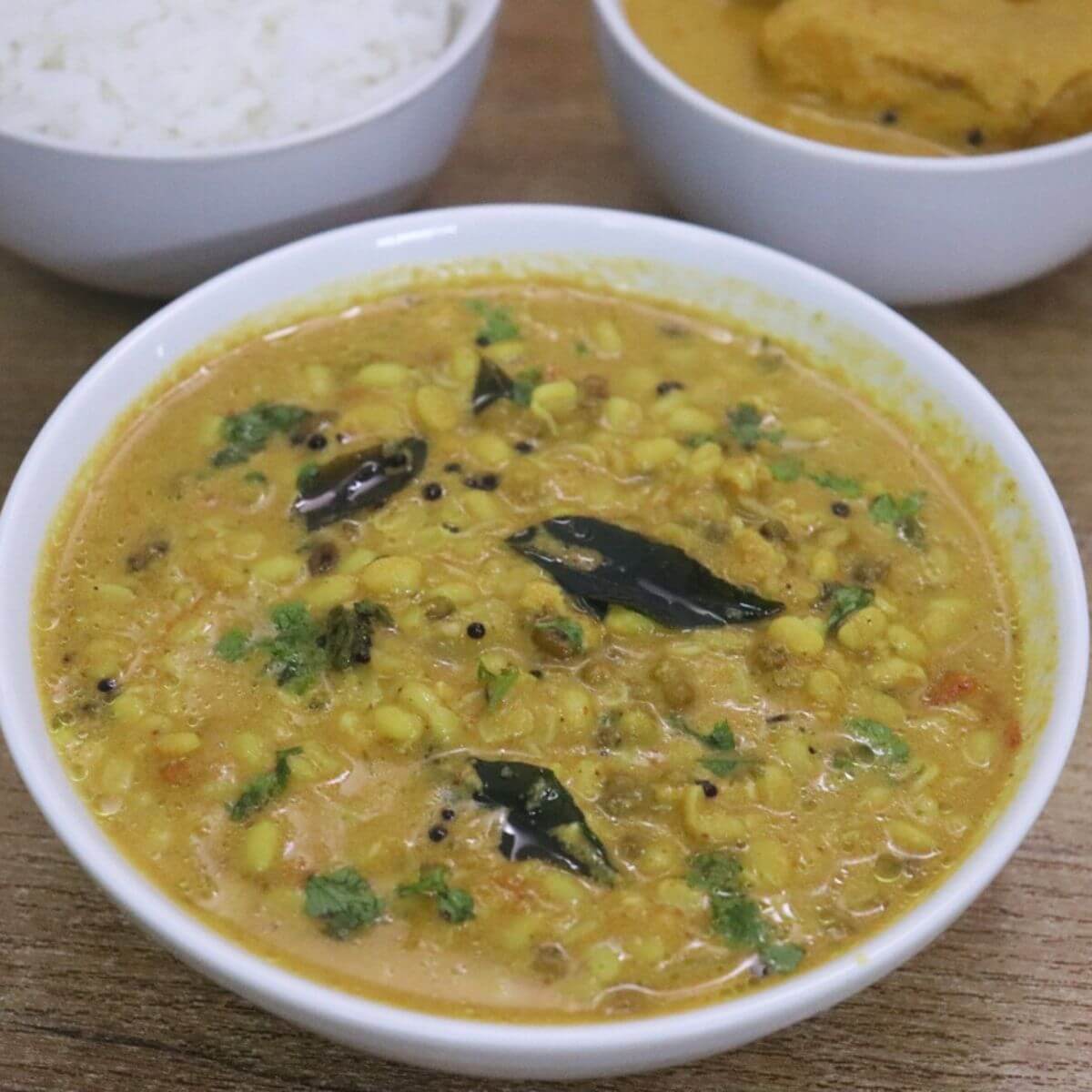 mooga gathi also known as sprouted green gram curry served in a white bowl.