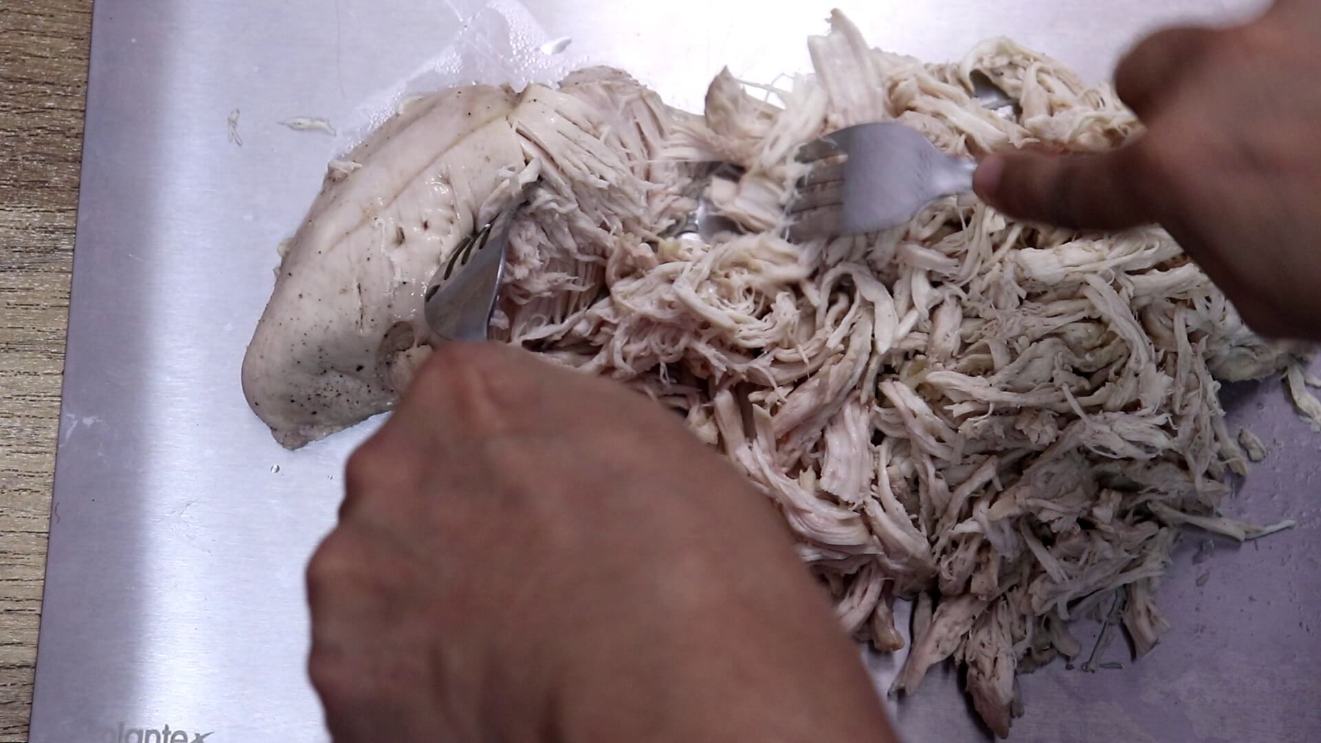 Pulling apart cooked chicken to make shredded chicken.