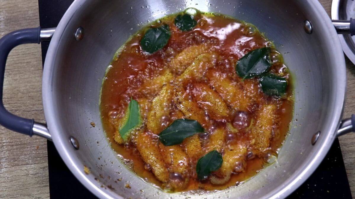 deep frying the silver fish in hot oil in a pan.