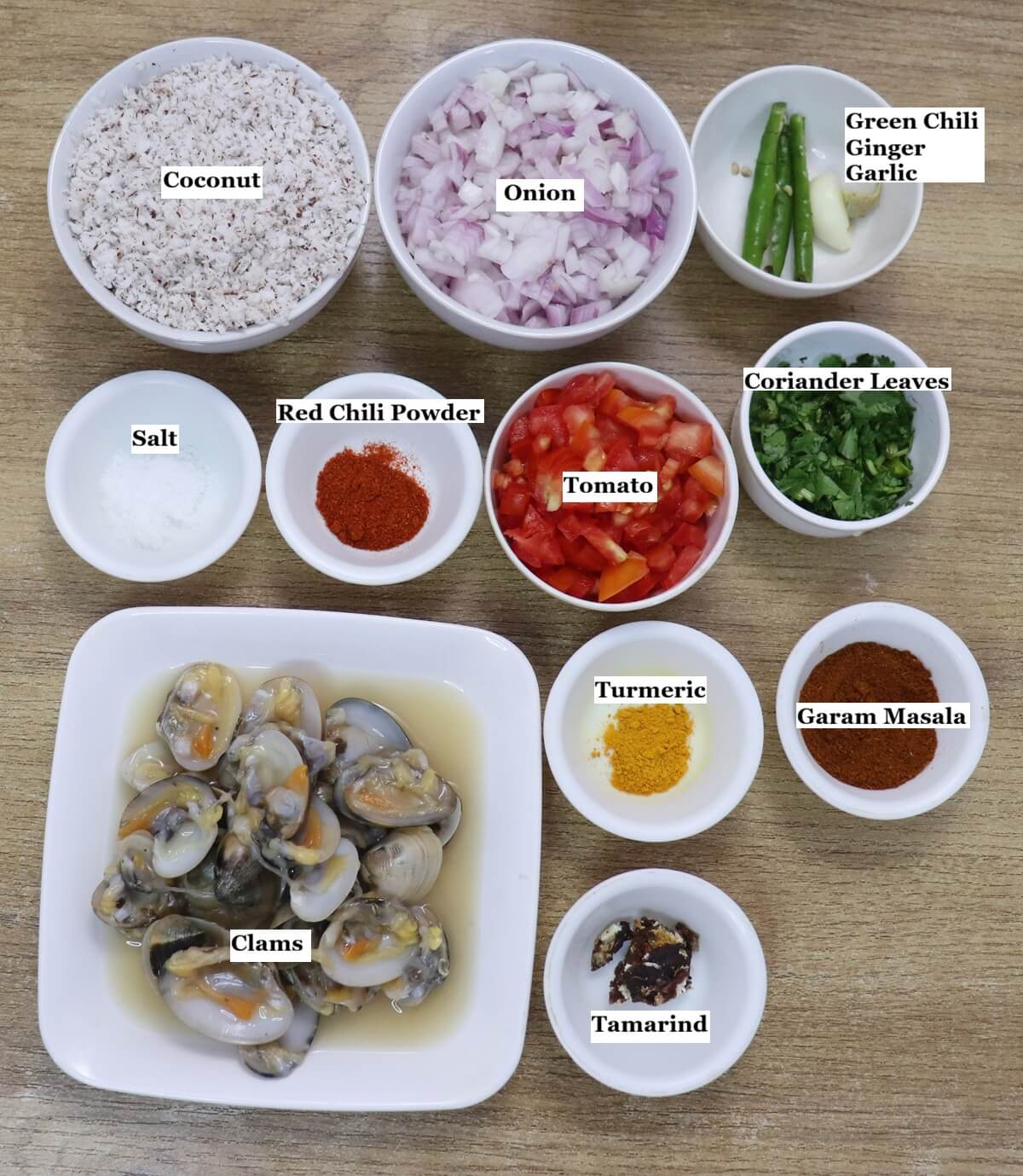 individually labelled ingredients to make goan clam curry are laid out on a table.