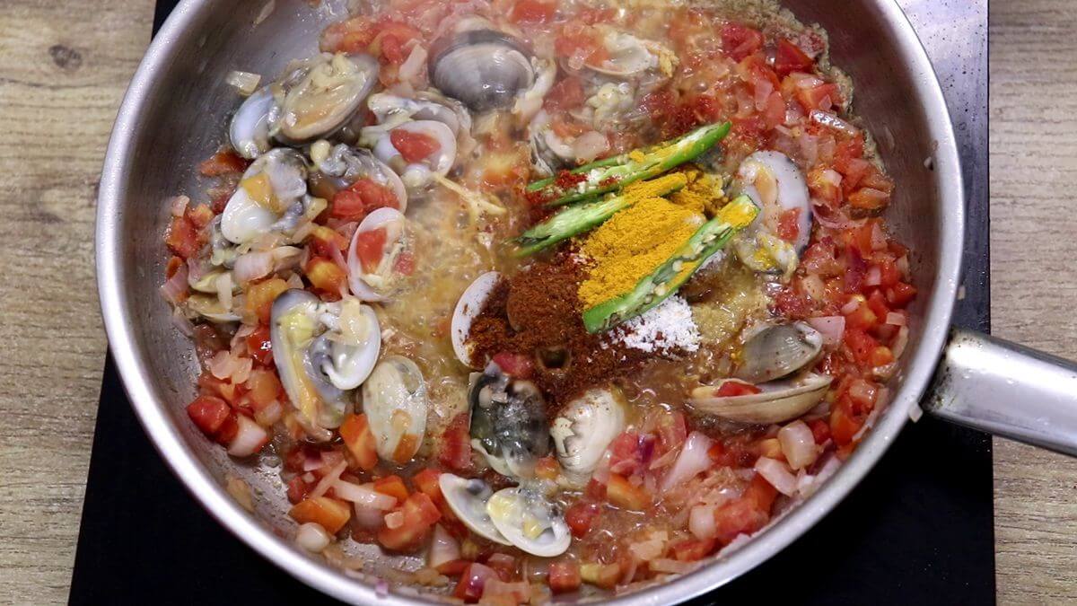 Adding clams and spices to the pan.