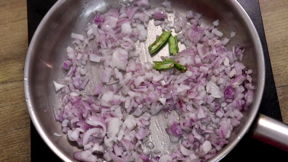 Sautéing chopped onions in a pan for tesri sukka.