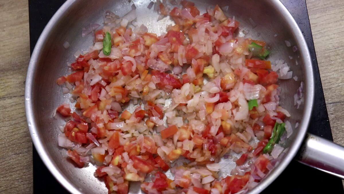 Adding chopped tomatoes to make the masala base.