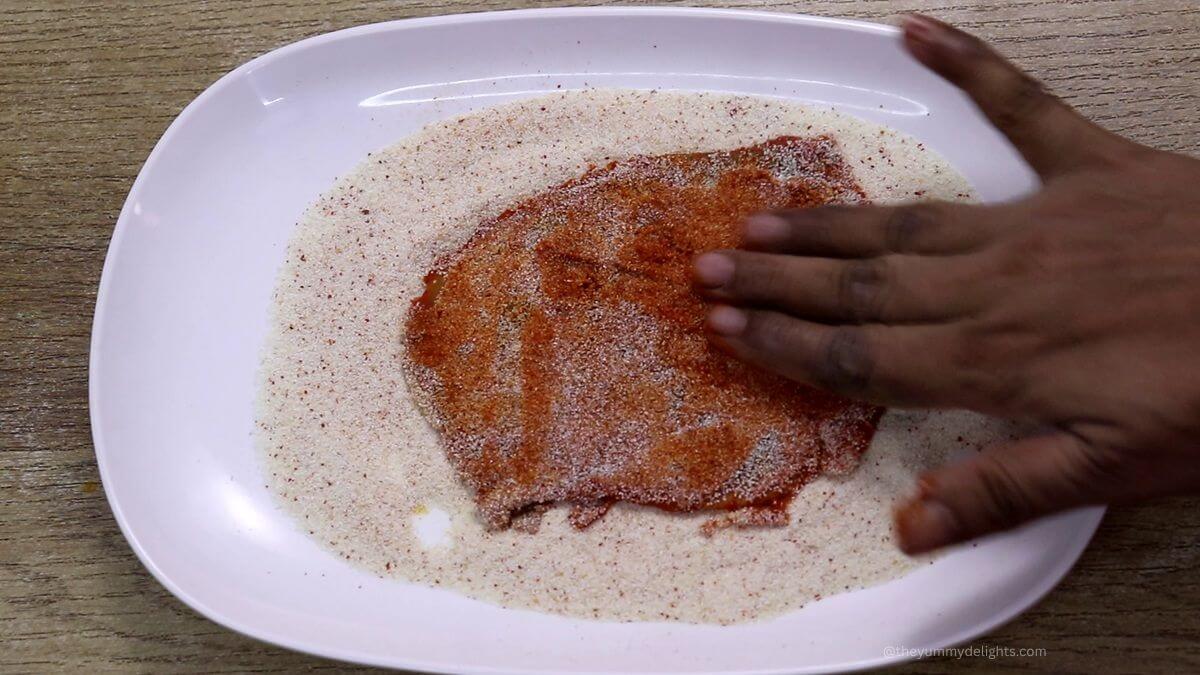Coating chonak fish with rava for crispy texture.