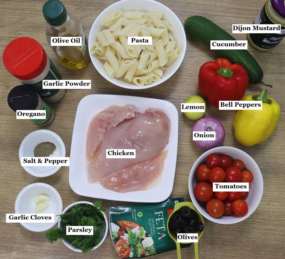 individually labelled ingredients to make lemon chicken pasta salad are laid out on a table.