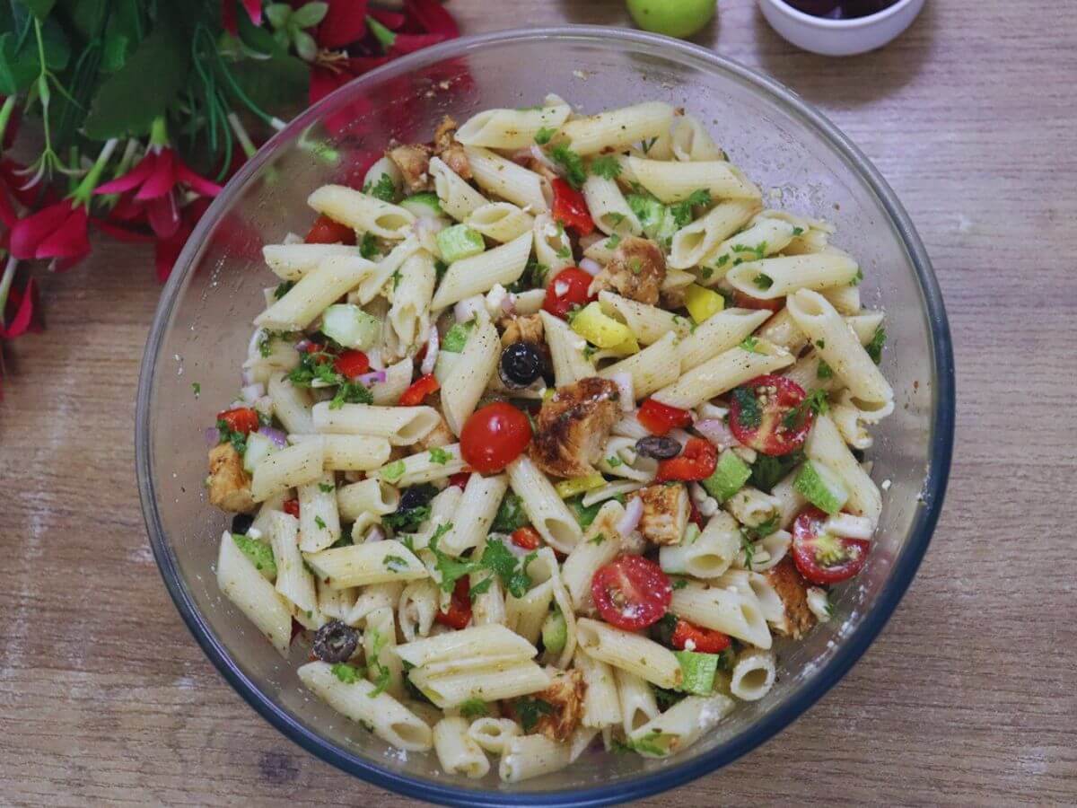 Lemon chicken pasta salad with feta, parsley, and cucumber in a glass bowl.