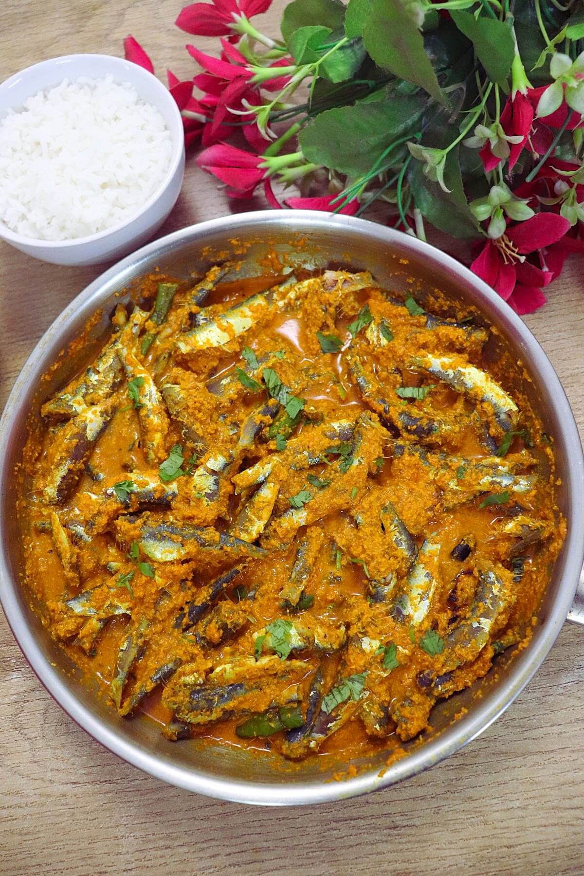 Fish sukka in a pan with a bowl of steamed rice on the side.
