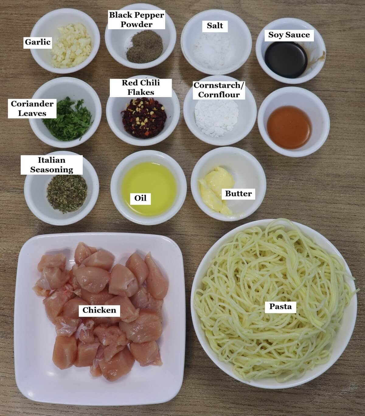 individually labelled ingredients to make garlic butter chicken pasta are laid out on a table.