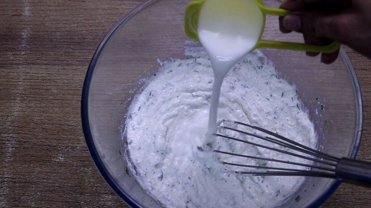 addition of milk for adjust the consistency of creamy Mediterranean greek yogurt dressing.