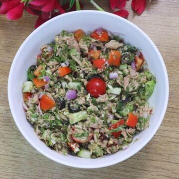 Mediterranean tuna salad served in white bowl garnished with dill leaves.