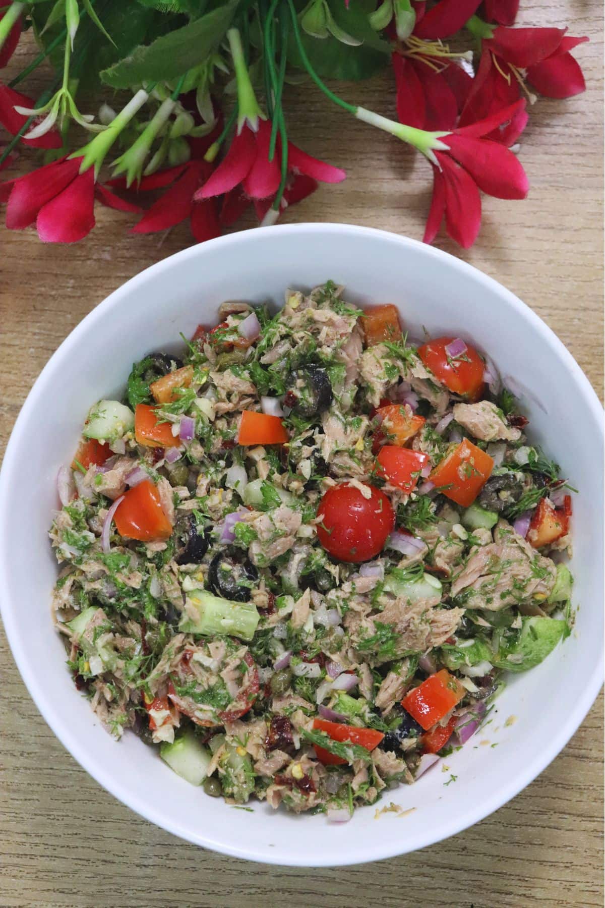Mediterranean tuna salad in a bowl over brown countertop.