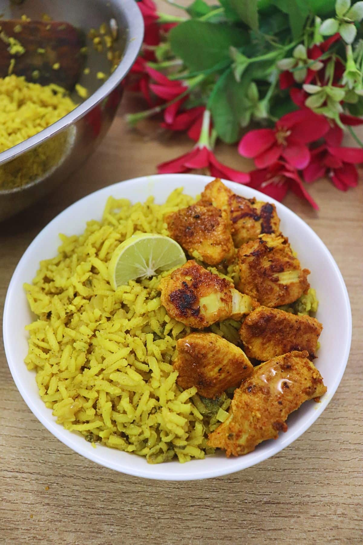 Mediterranean style yellow rice served in a white bowl with tandoori chicken bites.