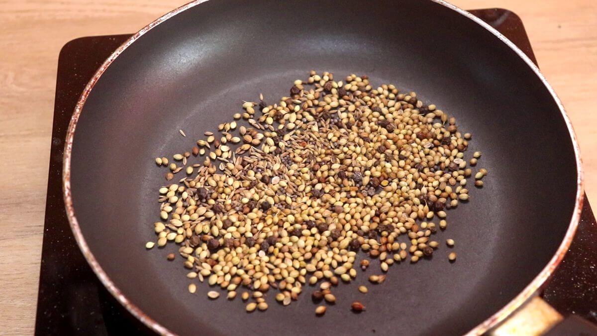 Whole coriander, cumin, mustard, fenugreek, and peppercorns dry roasting for homemade ghee roast masala.