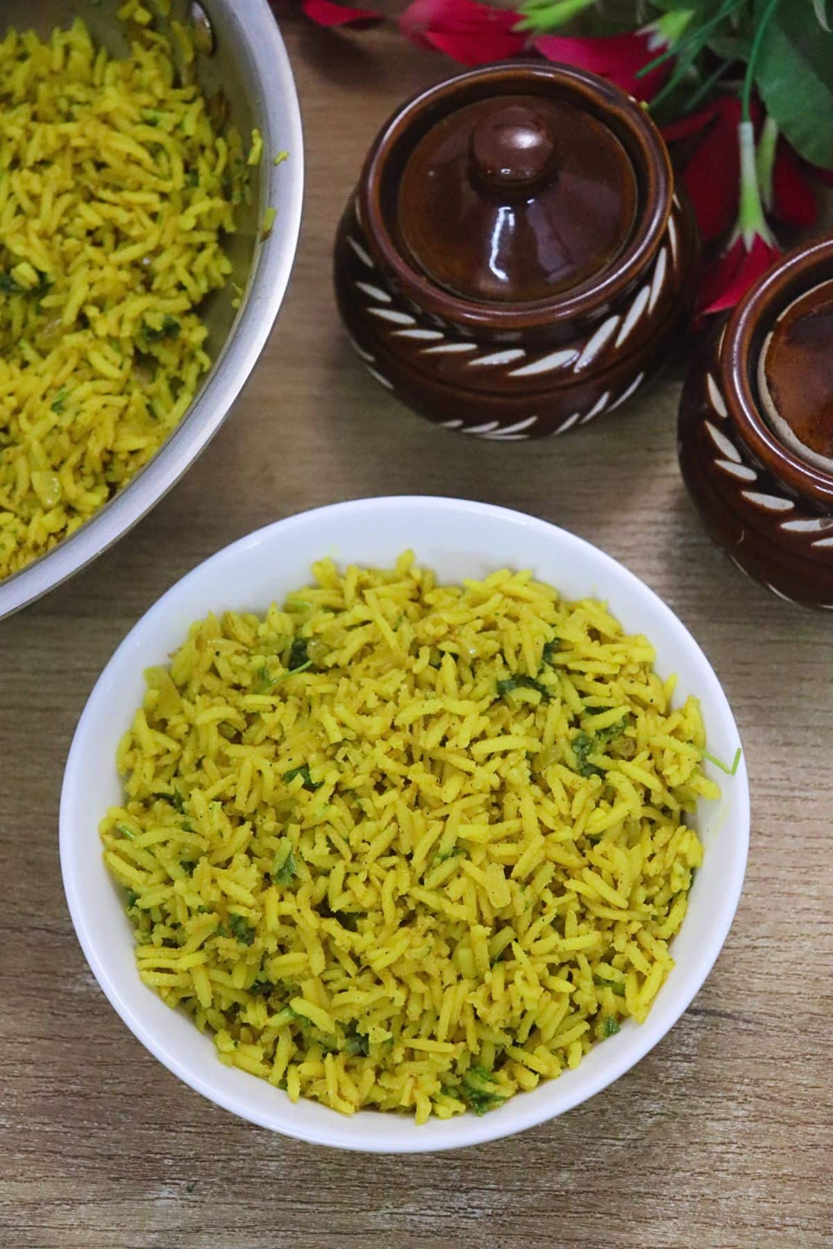 yellow turmeric rice served in a white bowl with some turmeric rice in a pot aside.
