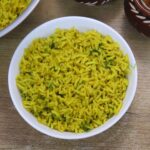 yellow turmeric rice served in a white bowl on brown countertop.