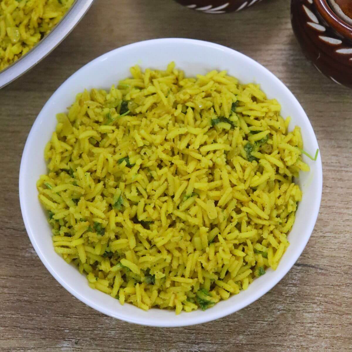yellow turmeric rice served in a white bowl on brown countertop.