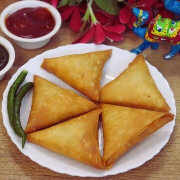 Chicken keema samosas served with green chutney and tomato ketchup.