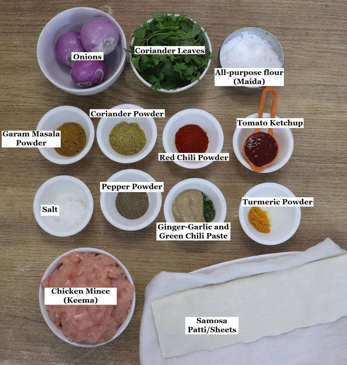individually labelled ingredients to make chicken keema samosa are laid out on a table.