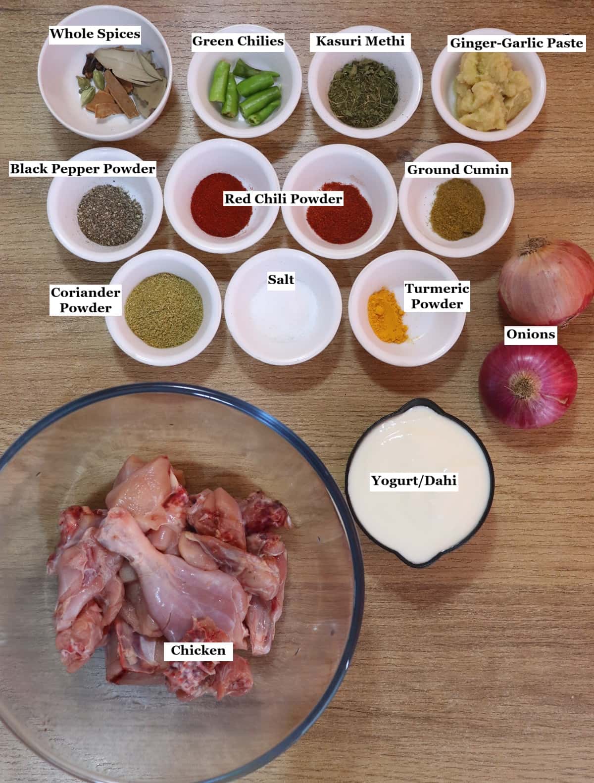 individually labelled ingredients to make dahi chicken recipe are laid out on a table.