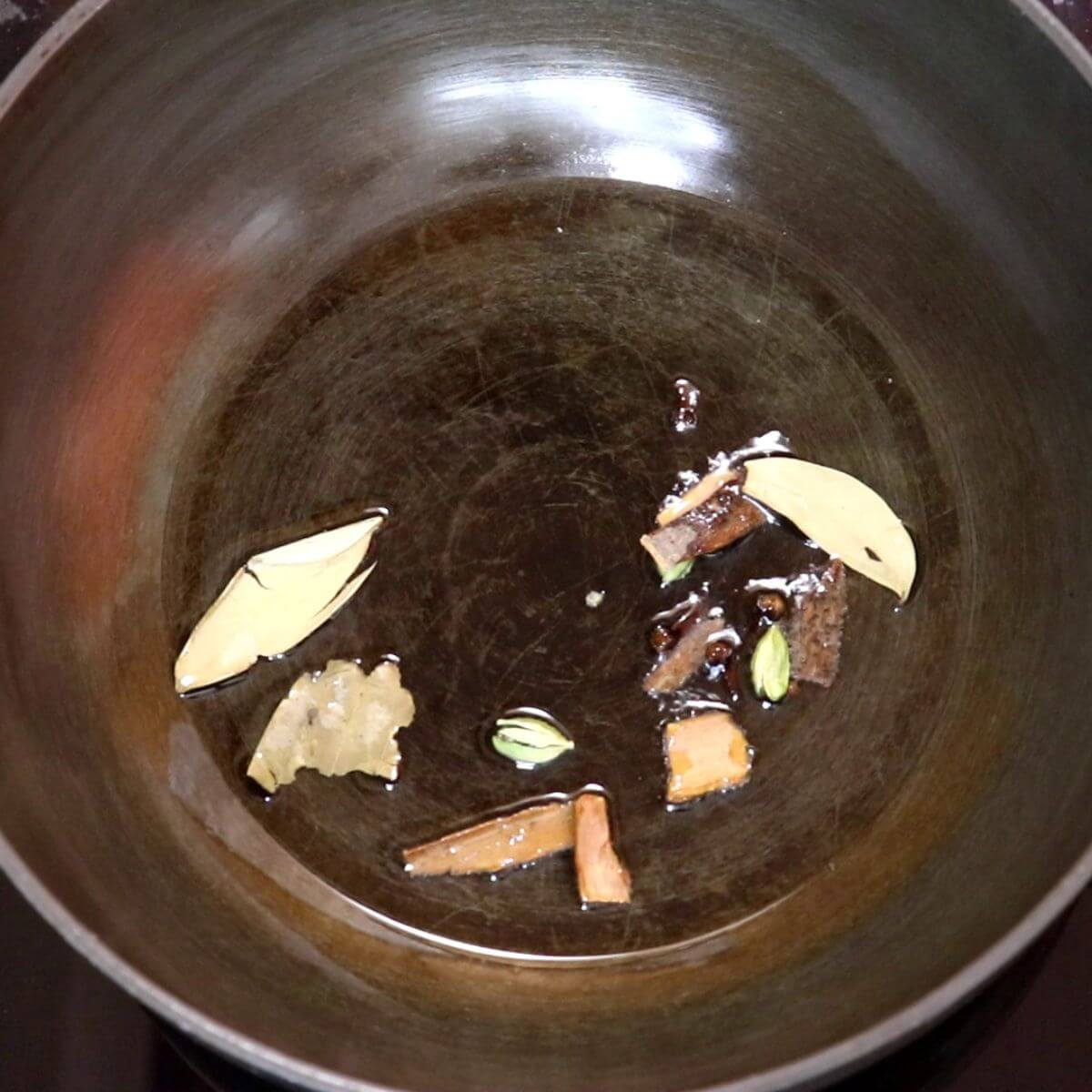 Whole spices sautéing in oil for dahi chicken.