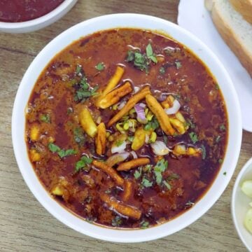 Kolhapuri Misal Pav served with tjick sliced bread, farsan, onions and lemon.